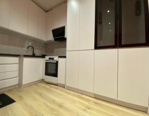 a kitchen with white cabinets and a wooden floor at Tirana Center Apartaments in Tirana