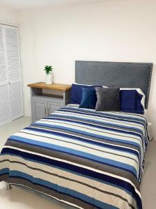 ein Bett mit einer blau-weißen gestreiften Decke in der Unterkunft Suite Jacarandas 103 in Guadalajara