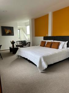 een grote slaapkamer met een groot wit bed met oranje muren bij PERUGINO´S HOTEL GALERIA in Popayan