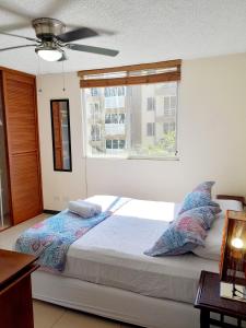 a bedroom with a bed with pillows and a window at Family condo, pool, beach and surf in Jacó