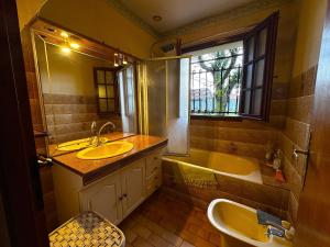 een badkamer met een wastafel, een bad en een raam bij Maison dans la forêt in Gujan-Mestras