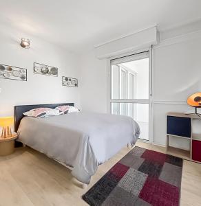 - une chambre blanche avec un lit et une grande fenêtre dans l'établissement Le Refuge d'Anjou, à Angers