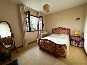 een slaapkamer met een bed, een tafel en een spiegel bij Maison dans la forêt in Gujan-Mestras