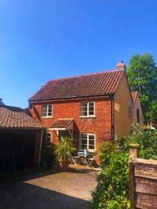 a red brick house with a porch and a garage at Southwell Holiday Cottage - Lavender Cottage in Southwell