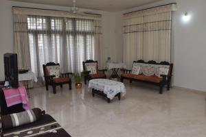 邁索爾的住宿－MAHAMAYA HOME STAY，客厅配有椅子、桌子和电视