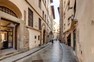 an alley in an old town with people walking down it at Golden House in Florence