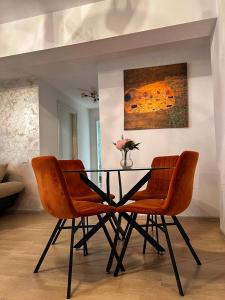 comedor con mesa de cristal y sillas naranjas en Wonderful Park Residences 5, en Bucarest