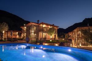 a large swimming pool in front of a house at night at Lithos Villas Apollon in Sikia