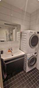 a bathroom with a sink and a washing machine at Relax in a cozy studio overlooking downtown in Tromsø