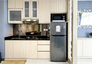 uma cozinha com um frigorífico e um micro-ondas em Apt Pejaten Park Biru 2 BR with Swim Pool, Bathub and Wi-Fi em Jakarta