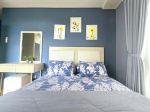um quarto com uma cama com paredes azuis e um espelho em Apt Pejaten Park Biru 2 BR with Swim Pool, Bathub and Wi-Fi em Jakarta