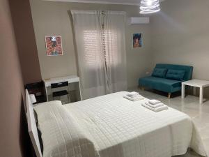 1 dormitorio con 1 cama y 1 sofá azul en Marconi Rooms and Apartaments, en Campobello di Licata