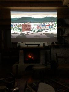 a television screen in a living room with a fireplace at Fireplace Chalet in Žabljak