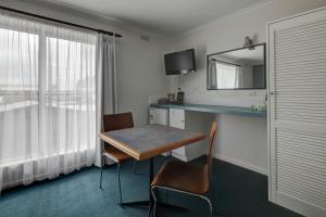 a hotel room with a table and a mirror at Central Motel Port Fairy in Port Fairy