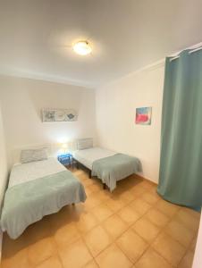 two beds in a room with blue curtains at Villa Marlau con piscina privada in La Oliva