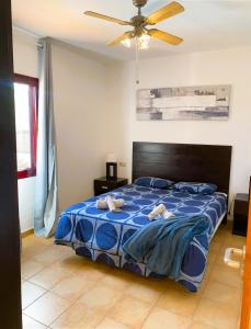 een slaapkamer met een blauw bed en een plafondventilator bij Villa Marlau con piscina privada in La Oliva