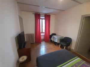 1 dormitorio con 1 cama y una ventana con cortinas rojas en La Flûte 2, en Thiers