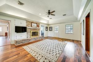 a living room with a fireplace and a ceiling fan at Expansive Texarkana Home with Yard Near Golf! in Texarkana