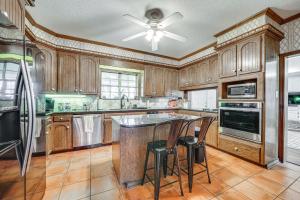 a kitchen with wooden cabinets and a large island with stools at Expansive Texarkana Home with Yard Near Golf! in Texarkana