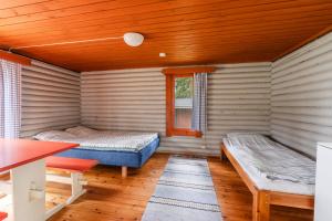 a room with two beds and a table in it at Lomakylä Timitraniemi in Lieksa
