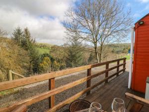 a wooden deck with a table and a fence at Red Kite at Wild Valley Huts in Oswestry