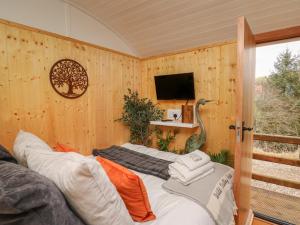 a room with wooden walls and a tv and a bed at Red Kite at Wild Valley Huts in Oswestry