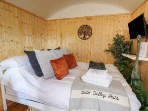 a bed in a room with wood paneled walls at Red Kite at Wild Valley Huts in Oswestry