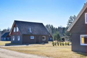 a brown house with a black roof and a yard at Mežezera stāsts in Pļaviņas