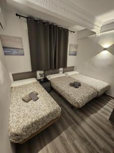 2 Betten in einem Zimmer mit zwei braunen Kissen in der Unterkunft Apartamentos Turia in Valencia