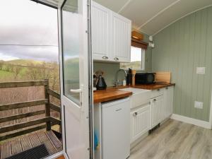 a small kitchen with white cabinets and a window at Cuckoo at Wild Valley Huts in Oswestry