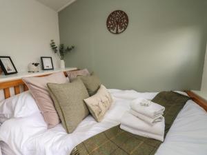 a white bed with pillows and towels on it at Cuckoo at Wild Valley Huts in Oswestry