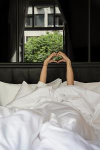 a person laying in bed with their hands forming a heart at The Modernist Thessaloniki in Thessaloniki