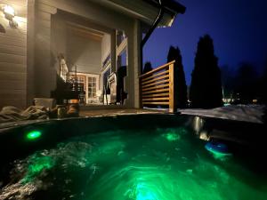 a hot tub with green lights in a backyard at night at Upea villa lähellä rantaa poreallas & SUP-laudat in Vaasa