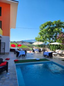 Andale SuiteSpa في Villa Badessa: مسبح بطاولات ومظلات على فناء