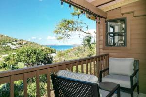 Un balcón con una silla y vistas al océano. en Seaside Studio: Cruz Bay Gem, en Enighed