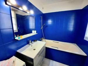 a blue bathroom with a sink and a bath tub at Le Sensation - En plein coeur de ville- ascenseur in Nîmes
