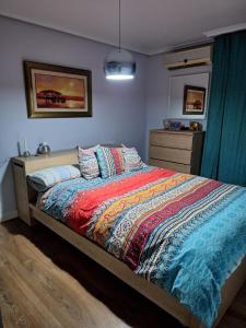 a bedroom with a bed with a colorful comforter at La pecera de Zoe in Córdoba