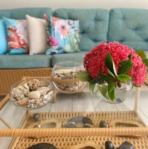una mesa de centro con un jarrón de flores rojas y rocas en Polinesia Resort - Porto de Galinhas - Apartamentos com somente 1 opção de Térreo com Piscina Privativa - Acesso ao Hotel Samoa, en Porto de Galinhas