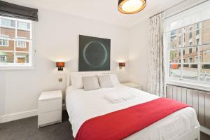sypialnia z dużym białym łóżkiem z czerwonym kocem w obiekcie Chelsea Diamond w Londynie