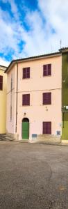 a white building with a green door on a street at La casetta del prato in Iesi
