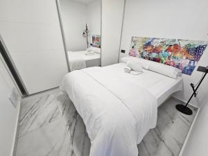 ein weißes Schlafzimmer mit einem Bett und einem Spiegel in der Unterkunft Apartamento Bacana Beach in Benidorm