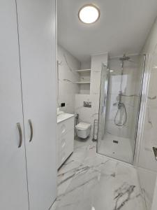 ein weißes Bad mit einer Dusche und einem WC in der Unterkunft Apartamento Bacana Beach in Benidorm