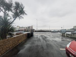 a parking lot with a palm tree and a car at Bay & Harbour Holiday Apartments & rooms only in Weston-super-Mare