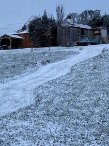 a snow covered field with a house and a dirt road at Stunning Shepherds Hut rural bliss Dumfries in Dumfries