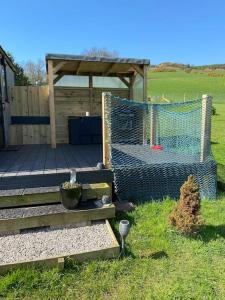 a backyard with a fence and a deck with a chicken coup at Stunning Shepherds Hut rural bliss Dumfries in Dumfries