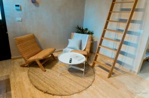 a living room with two chairs and a ladder at Hagafen Boutique Suites in Zikhron Ya‘aqov