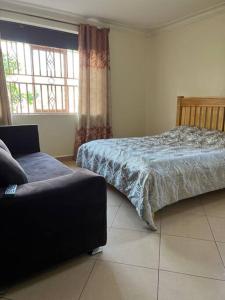a bedroom with a bed and a couch and a window at MD comfort living in Kampala