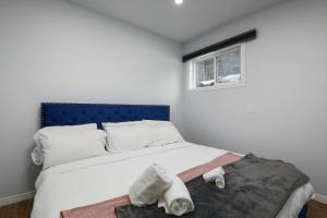 a bedroom with a bed with a blue headboard and a window at The Nordic 2BR Chalet by Instant Suites - 5 min to Tremblant Village in Mont-Tremblant