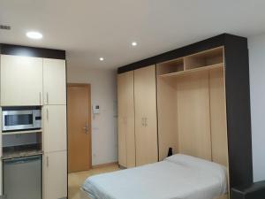 a small bedroom with a bed and a microwave at Estudio Céntrico A1 in Oviedo