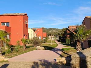 a walkway through a town with houses and palm trees at T3 Picchiarini, Clim, piscines, resto, 5' plages in Lecci